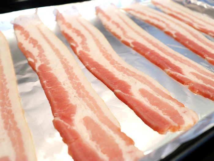 Bacon tips - raw bacon sliced on aluminum foil for baking