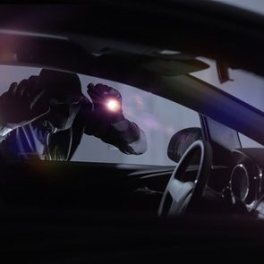Car anti-theft devices - car thief looking in car with flashlight