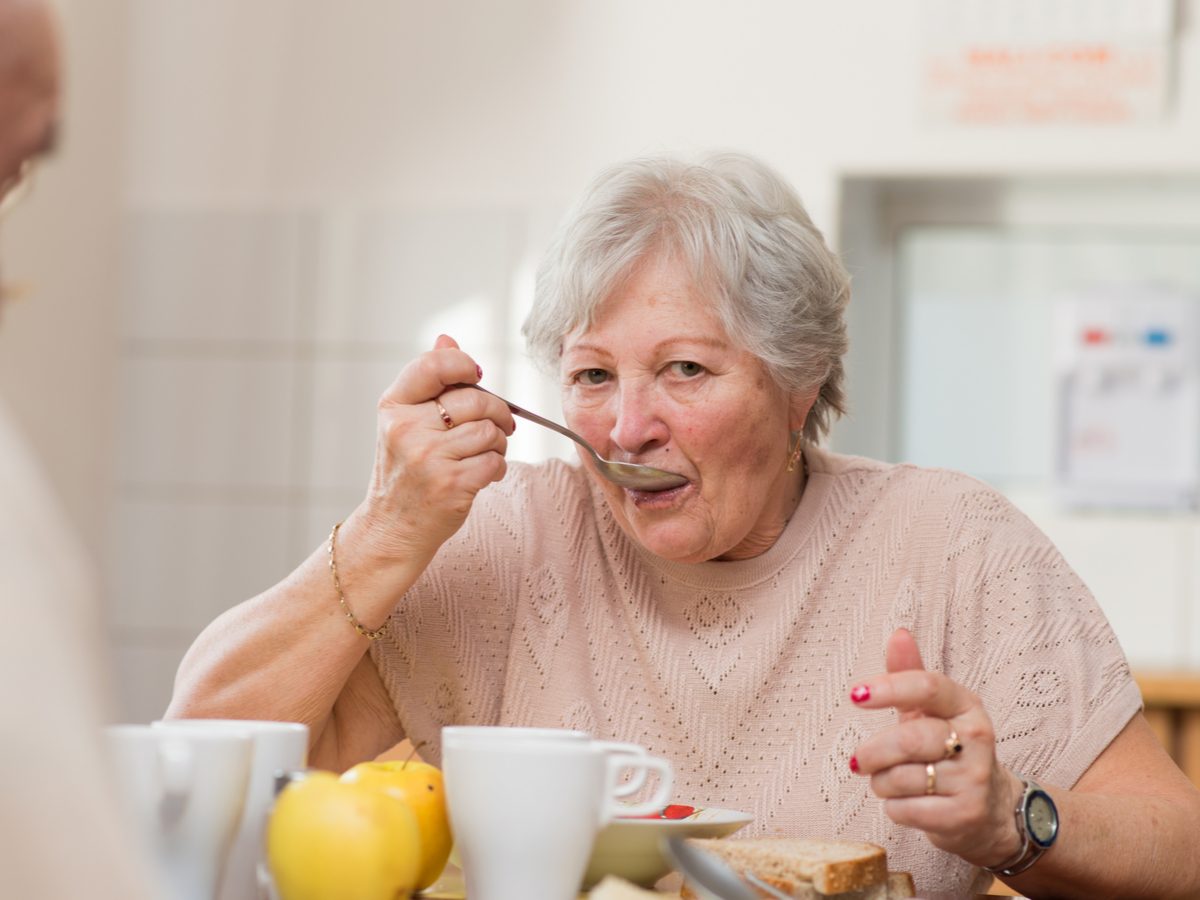 Senior woman eating breakfast at dining room table