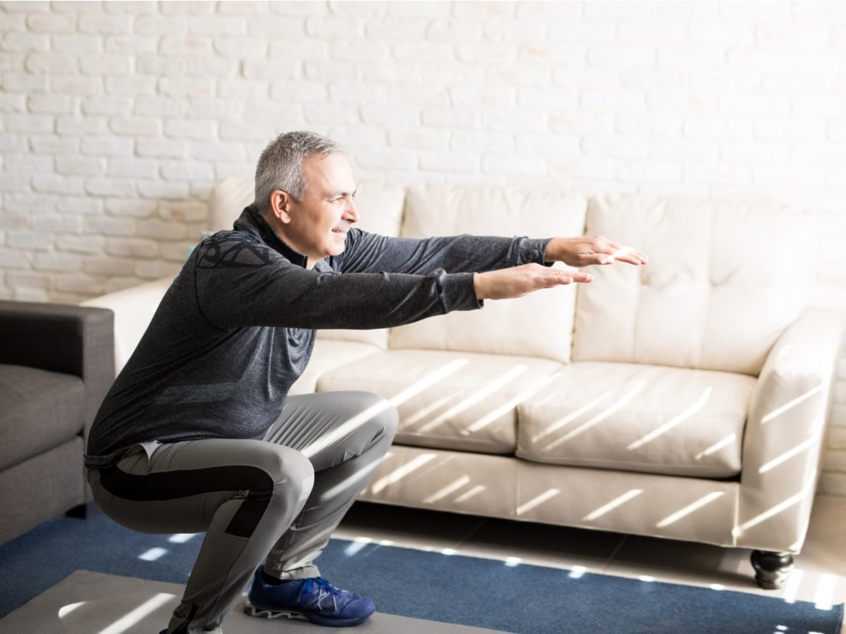 Middle-aged man stretching in his living room