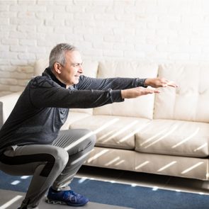 Middle-aged man stretching in his living room