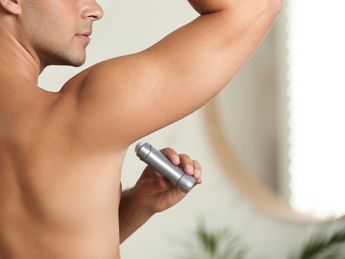 How To Sweat Less This Summer - Person applying deodorant