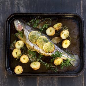 Delicious baked rainbow trout straight from the oven with potato, lemon and herbs.