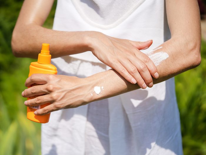 Sunblock tips - A young girl in a white summer dress applies sunscreen gel to her arms and shoulders, a woman takes care of her skin on a sunny day.