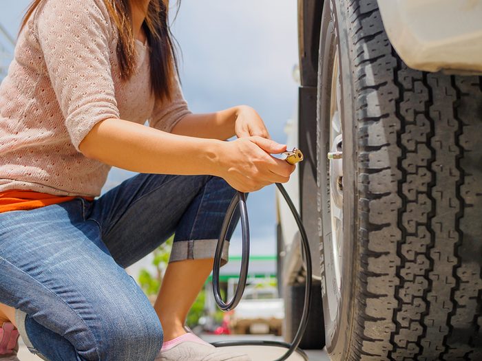 Car tire maintenance - driver checking air pressure and filling air in the tires close up