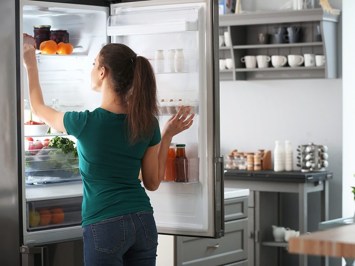 Shortening the life of your fridge - woman reaching in refrigerator