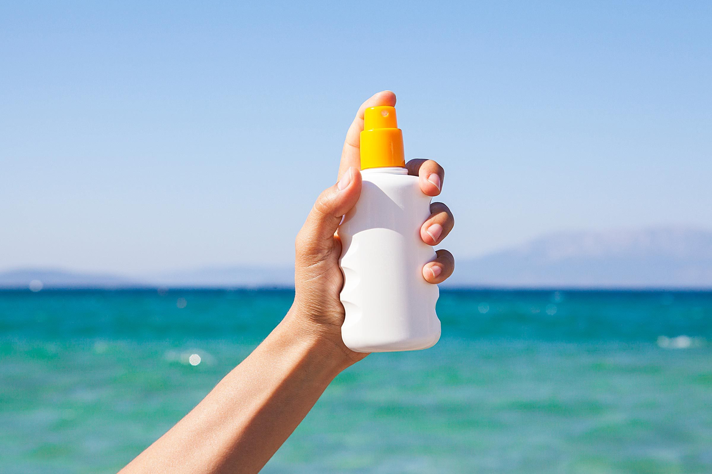 hand sunscreen bottle beach ocean water
