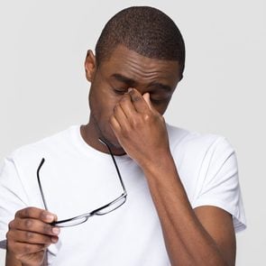 bad eating habits - Tired african american man massaging nose bridge taking off glasses feeling eye fatigue strain isolated on white grey studio background, young black guy having headache dry irritable vision problem