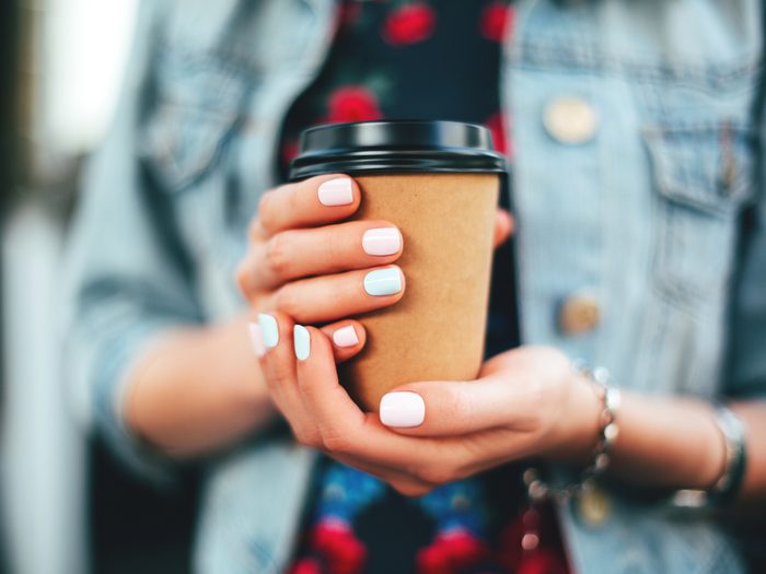 caffeine benefits and risks - Woman holding paper cup of coffee take away