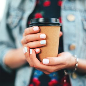 caffeine benefits and risks - Woman holding paper cup of coffee take away