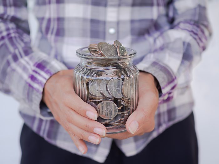 Future plan saving money for 2021 year concept. Close up farmer hand holding coin in jar.