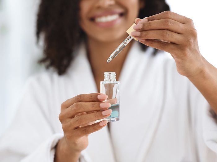 Brain exercises - Beauty And Skincare. Smiling Black Woman Holding And Opening Bottle With Moisturizing Face Serum, Making Skin Treatment At Home, Closeup