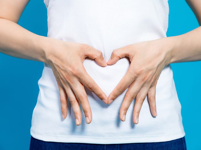 how to improve gut health - young woman who makes a heart shape by hands on her stomach.