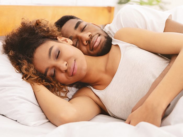 Secrets to a good night's sleep - couple cuddling in bed
