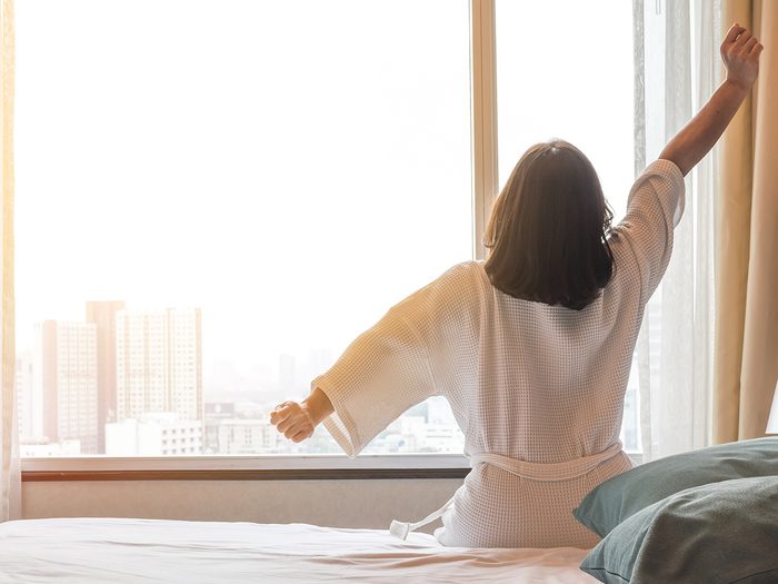 Secrets to a good night's sleep - woman waking up in hotel room