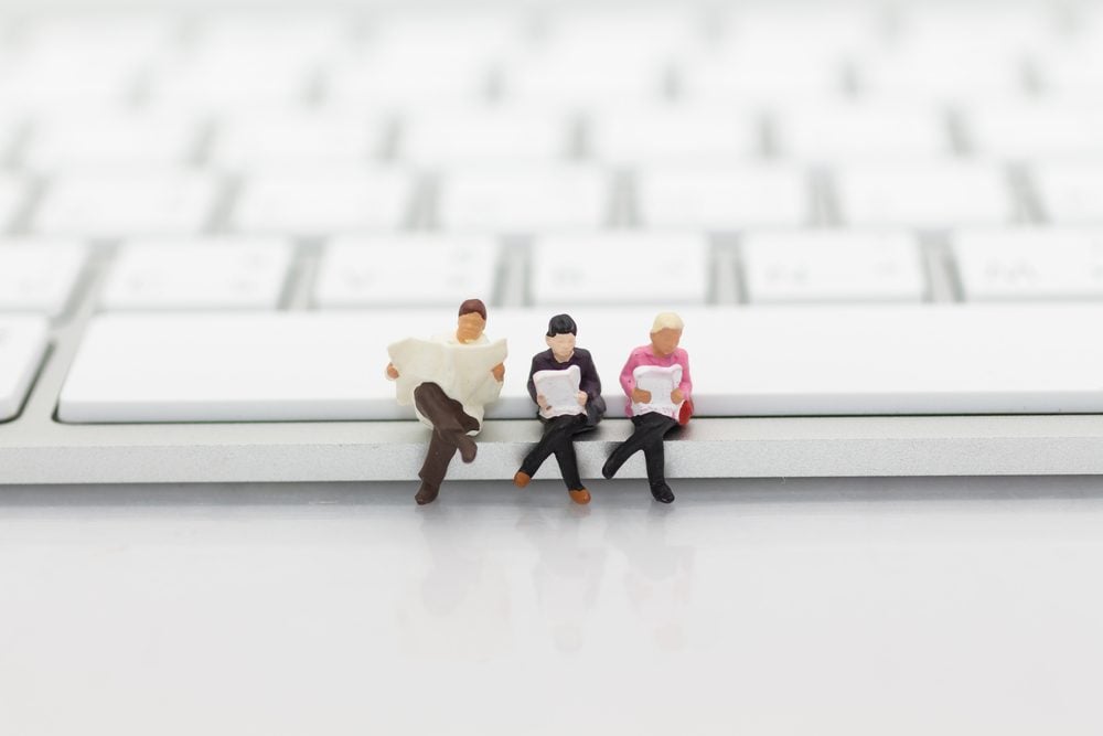 Miniature people sitting on keyboard using as background education or business concept.