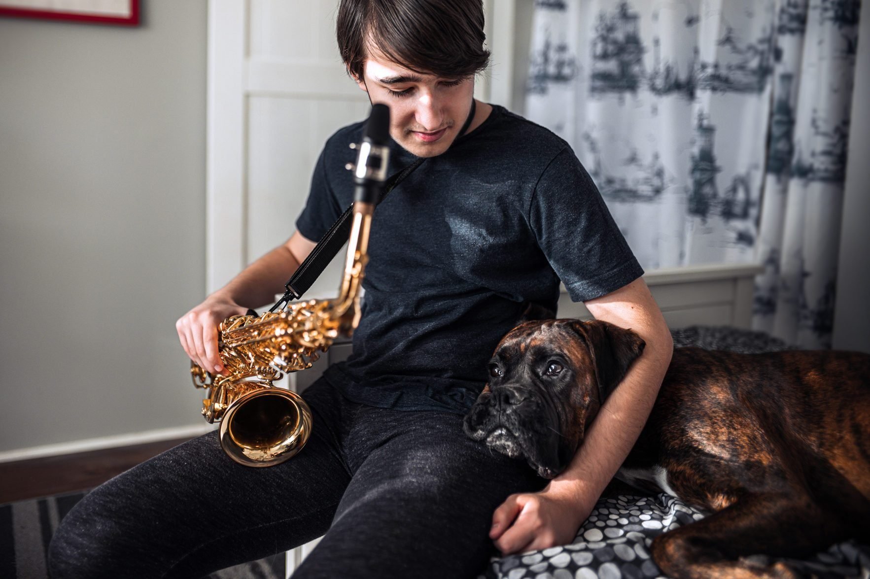 Most affectionate dog breeds - Teenager playing sax in his room