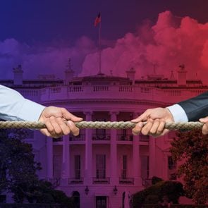 two businessmen pulling on a rope, tug-o-war style. White House background with red-to-blue fade overlay.