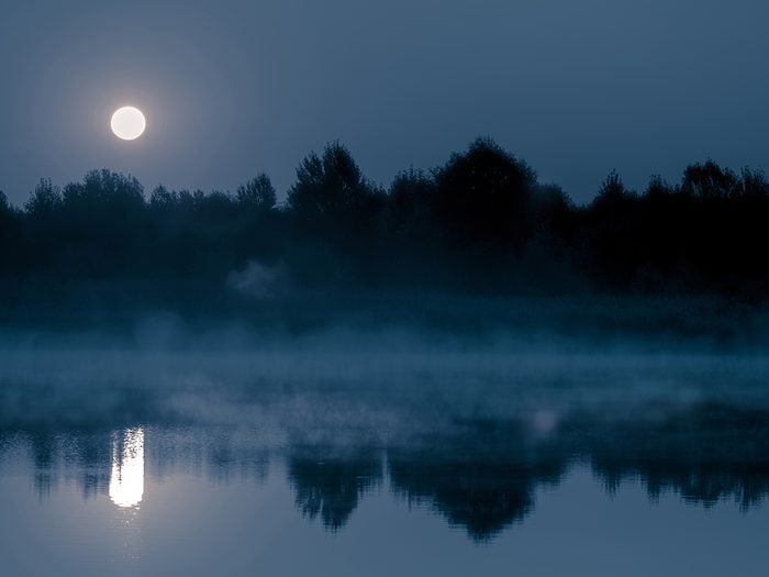 Creepy facts Canada - Night mystical scenery. Full moon over the foggy river and its reflection in the still water.