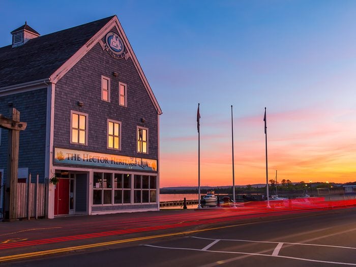Day trips from Halifax - Hector Heritage Quay museum and flagpoles in sunset light with car tail light trails in the foreground.