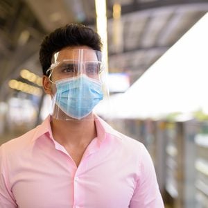 Do face shields really stop coronavirus - man wearing mask and face shield at train station