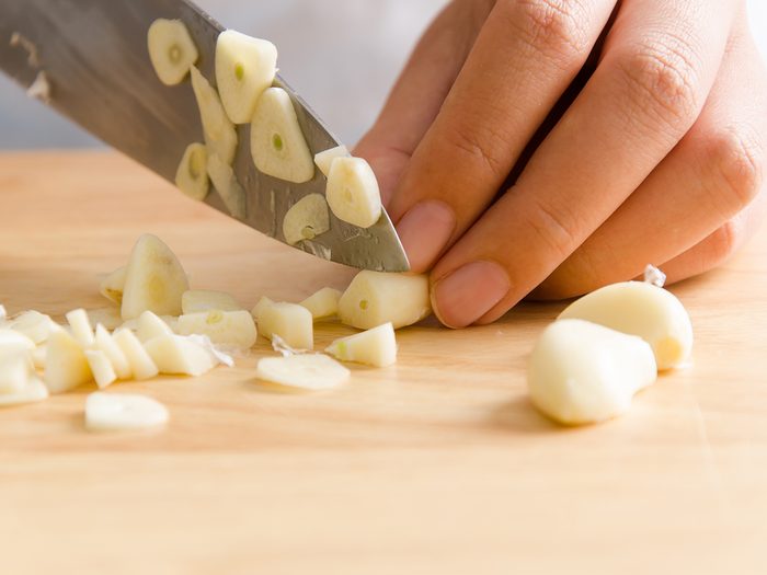 Easy way to peel garlic - Woman chopping garlic on wooden board for cooking