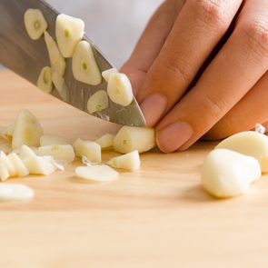 Easy way to peel garlic - Woman chopping garlic on wooden board for cooking