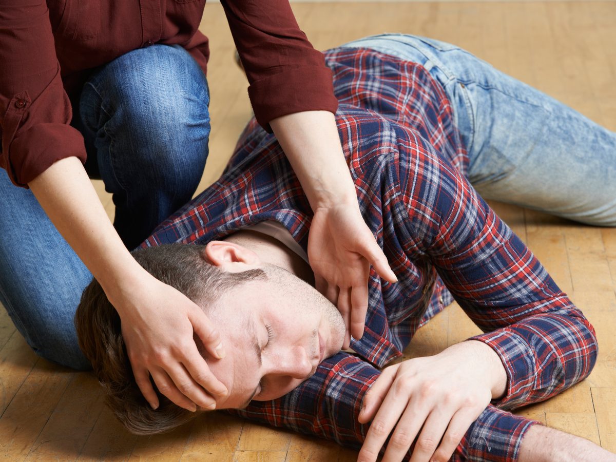 Woman tending to man in recovery position