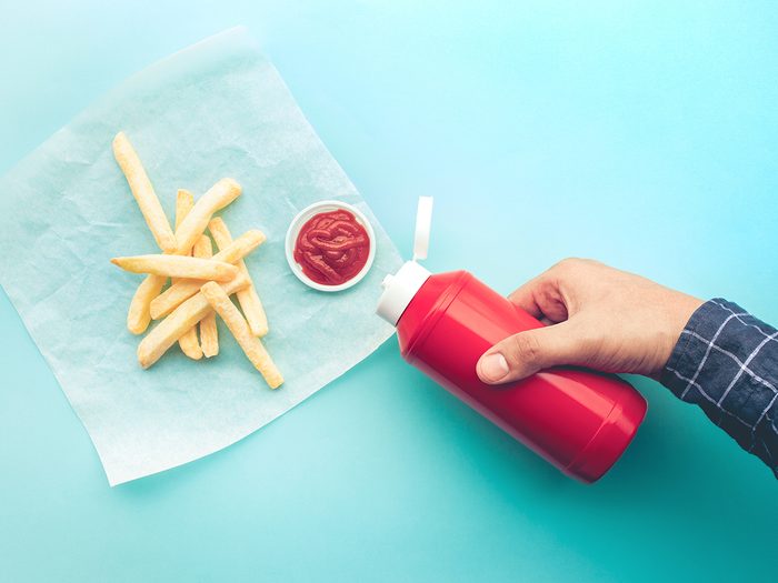 Ketchup bottle - Top view of youngman squeezing a bottle sauce on french fries