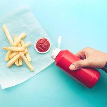 Ketchup bottle - Top view of youngman squeezing a bottle sauce on french fries