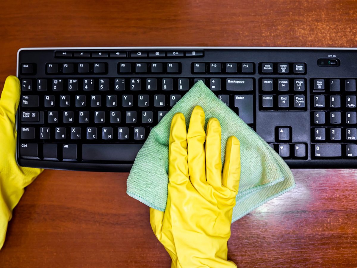 Mistakes you're making with disinfectant - Woman in rubber gloves disinfects the keyboard
