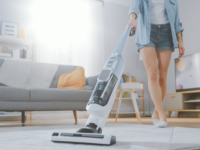 Vacuum cleaner - Woman vacuuming living room carpet