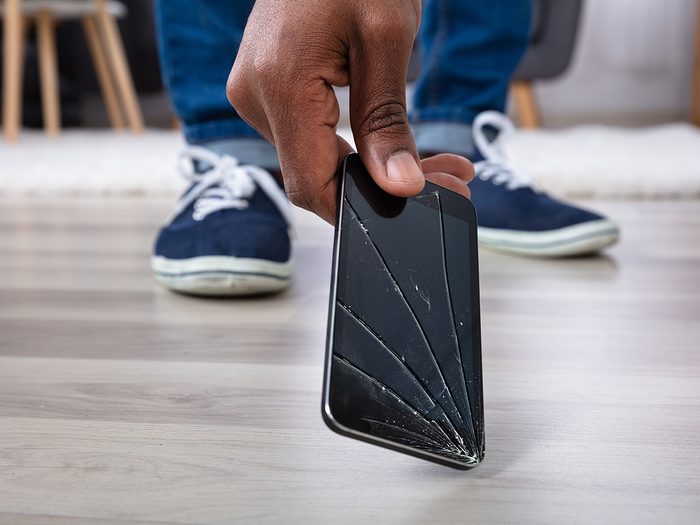 Man's Hand Picking Up Mobile Phone With Broken Screen