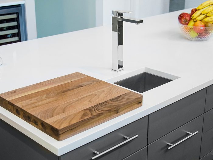 Kitchen counter with cutting board faucet, sink and plate of fruits