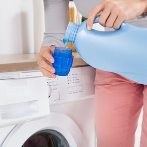 Uses for laundry detergent - Woman pouring detergent in washing machine