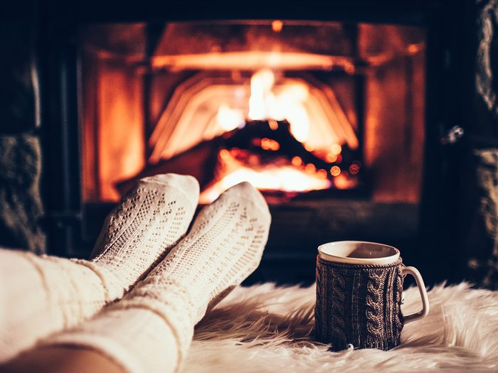 cozy home - Person sitting in front of fireplace with feet up and mug