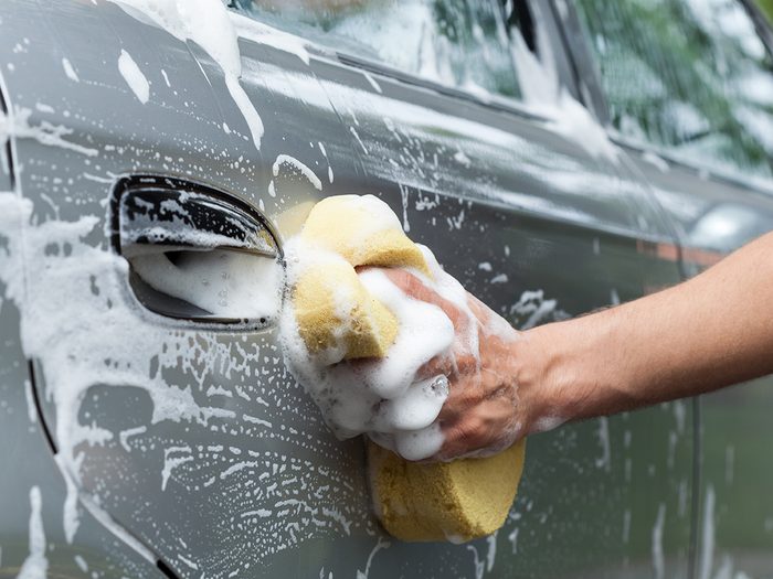 Person cleaning car with sponge