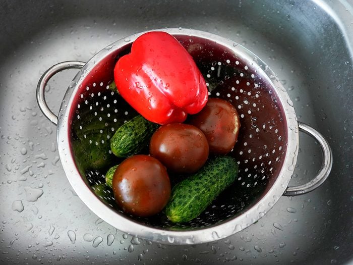 Washing produce in colander in sink