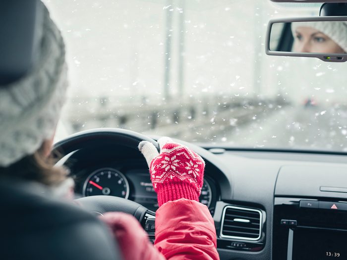 Winter road trip - woman driving through blizzard