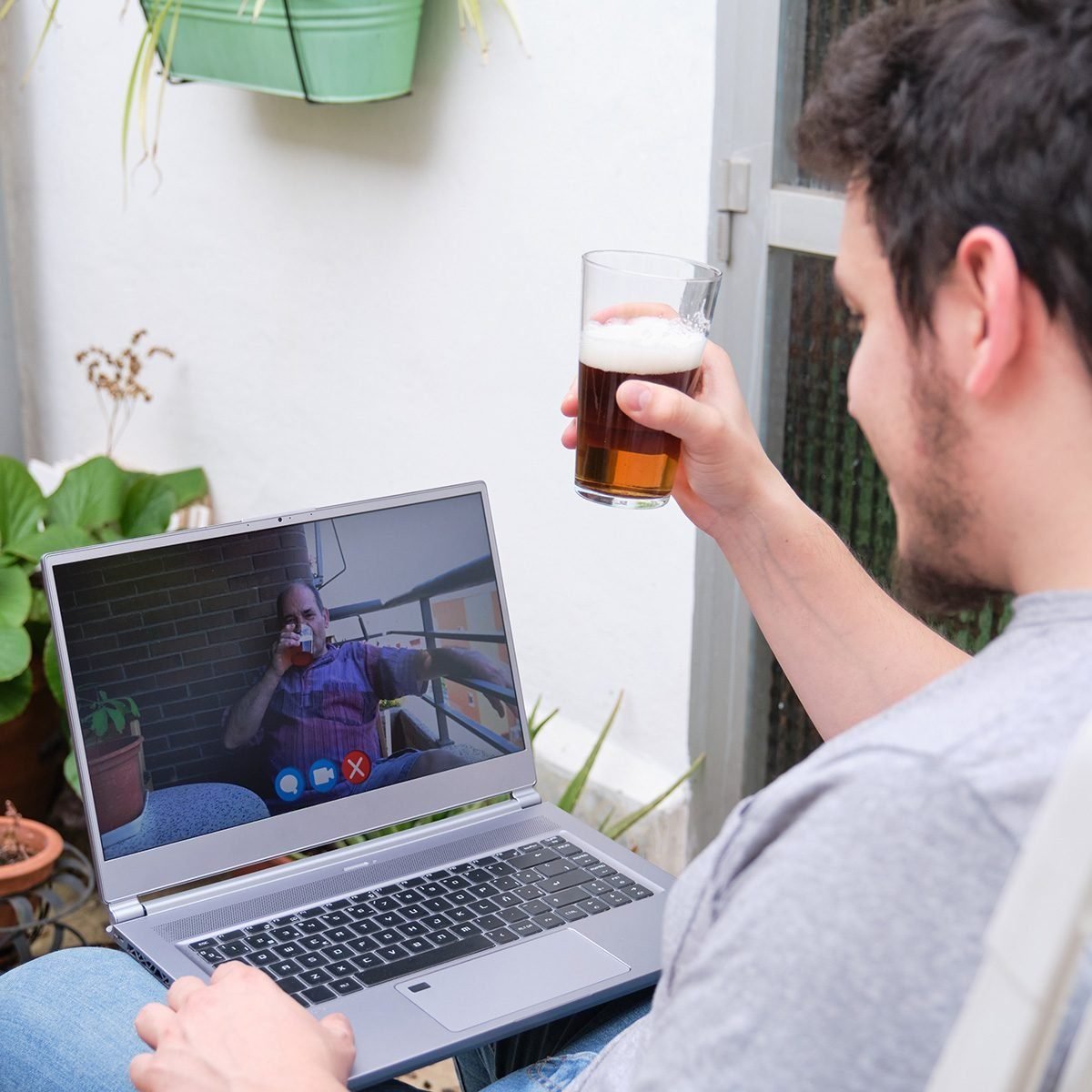 Man Talking And Having A Beer With His Father On A Videocall