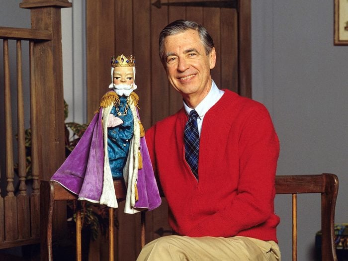Mr. Rogers sitting and holding a puppet.