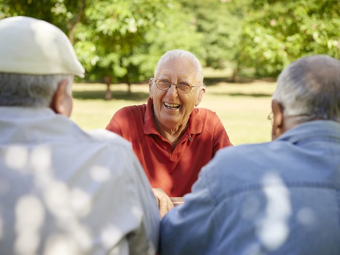 Senior man laughing with friends in park