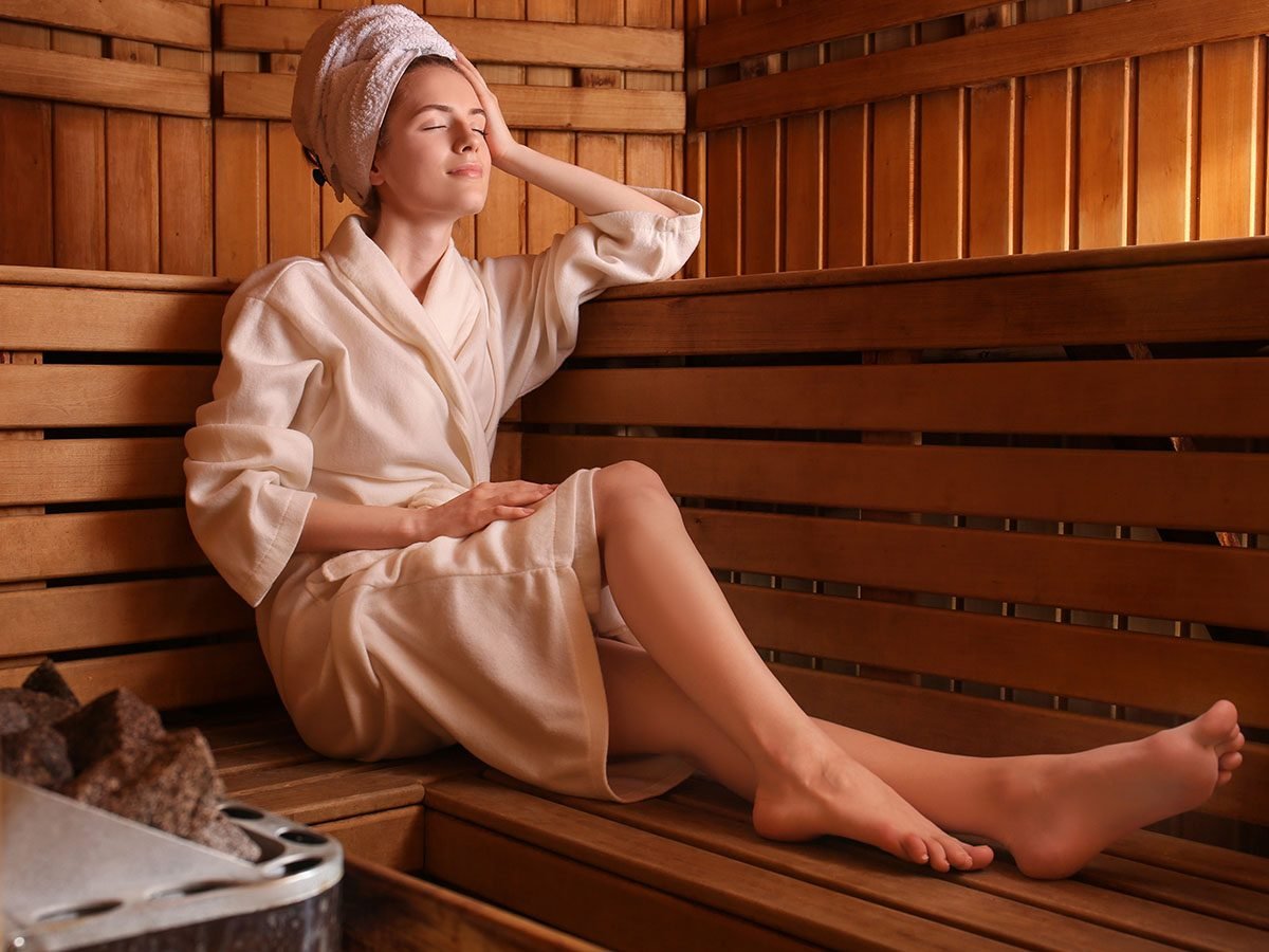 woman sitting on wooden bench in sauna.