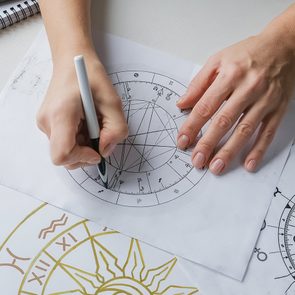Why is astrology so popular today - Astrologer studying star charts and astrology symbols