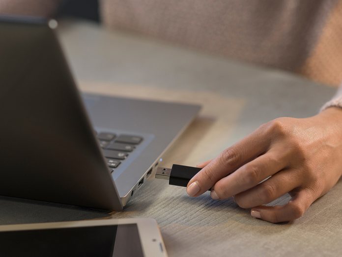 Woman plugging a USB drive into her laptop, technology and data storage concept