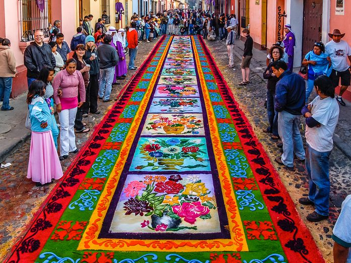 Easter Traditions Antigua - Locals & tourists admire dyed sawdust carpet made overnight for Good Friday procession in Antigua, Guatemala