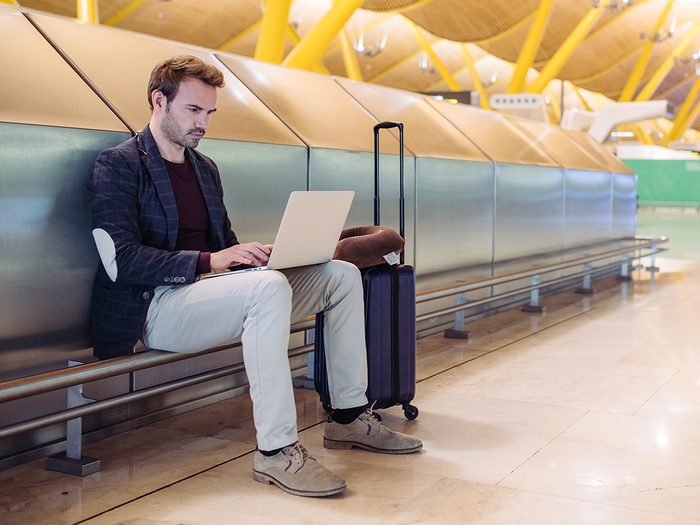 Man on laptop using public wifi at airport