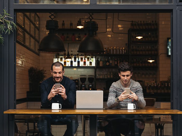 Two men accessing coffee shop wi-fi