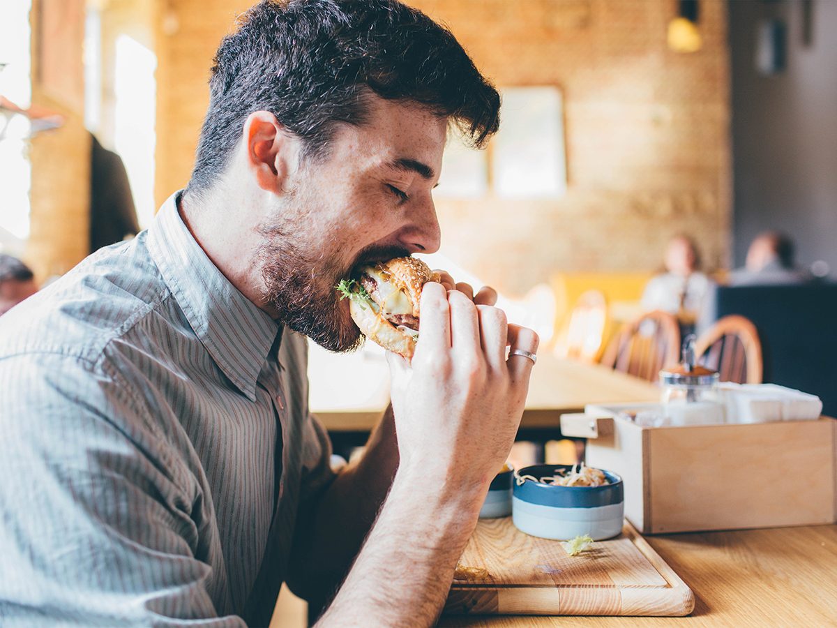 What constant burping means - man eating hamburger quickly