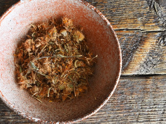 A top view image of dried Arnica herbs in a decorative pottery bowl.